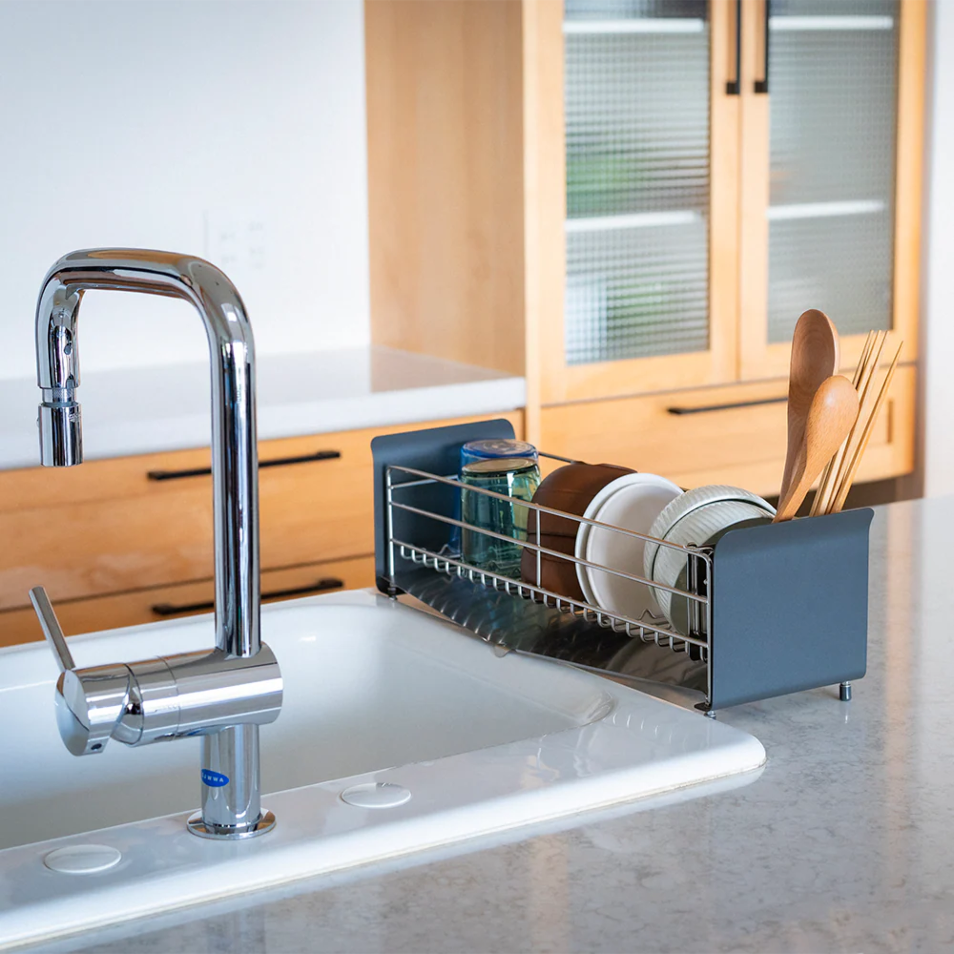 UtaU Dish Drainer Short calm gray over-the-sink rack holding plates, bowls, glasses and wooden utensils in modern kitchen