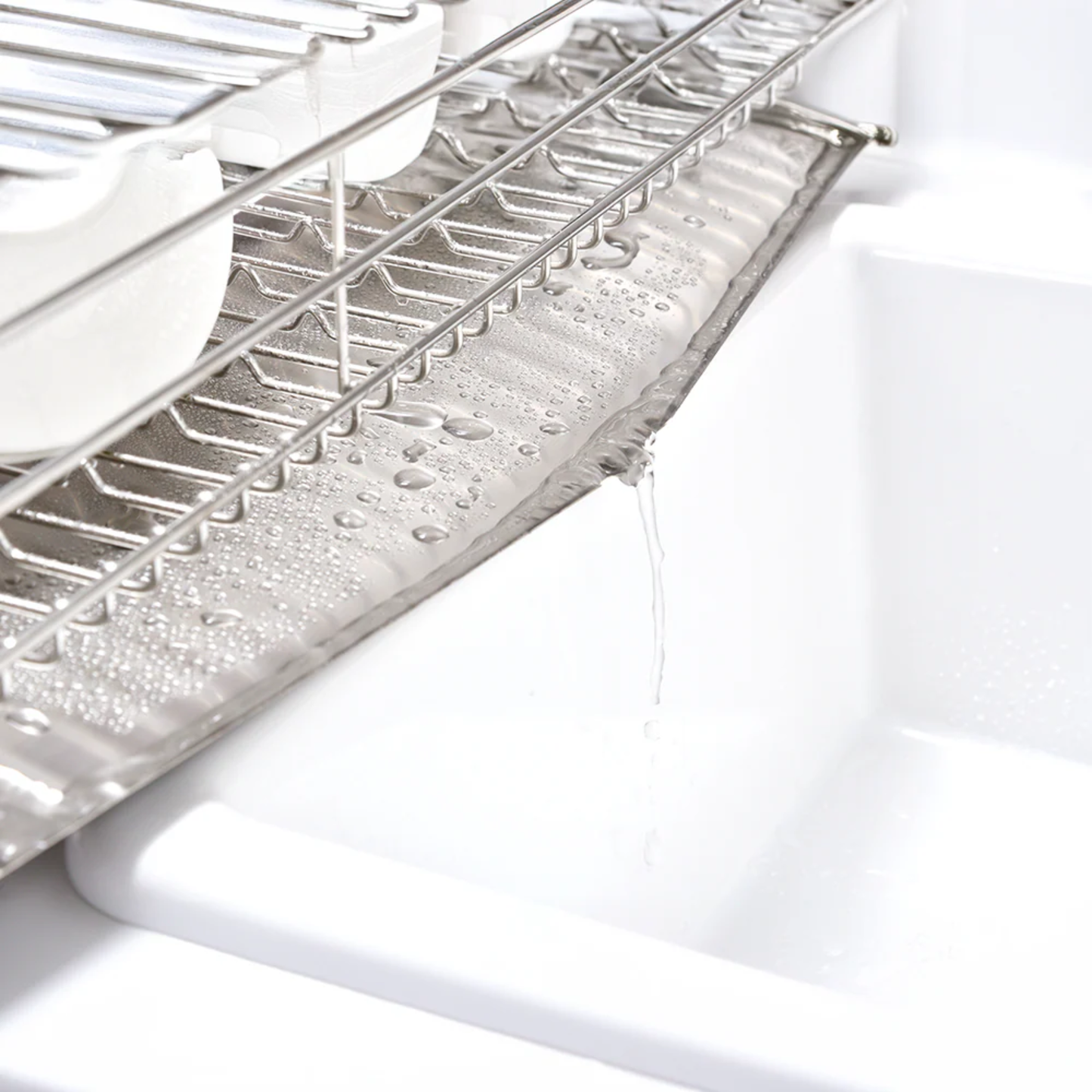 Close-up of UtaU Dish Drainer Short pure white showing stainless steel rack and sloped drip tray draining water into sink