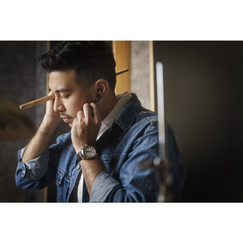Musician in a studio setting using Attenu8 earplugs for noise protection while playing drums, ideal for musicians and performers, available at Ideale Lifestyle e-commerce store