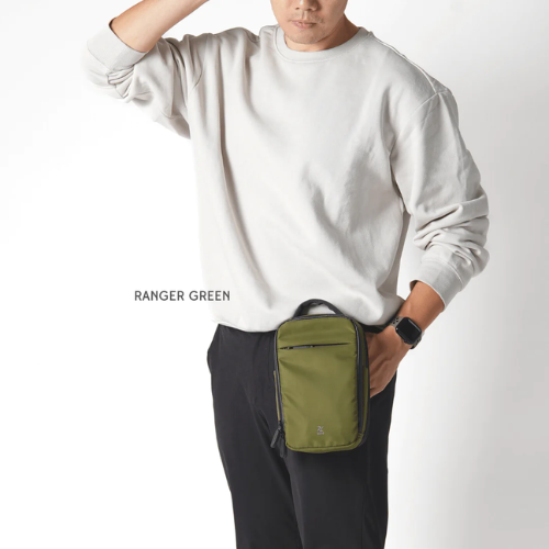 Bold Ranger Green compact crossbody sling bag, minimalist design with black trim, worn by man in white sweatshirt and black pants, casual fashion style